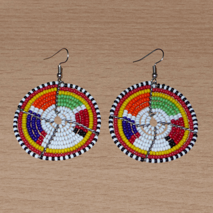 Boucles d'oreilles africaines de tradition tribale Massai composées de perles de rocaille blanches et multicolores montées en forme de disques. Elles mesurent 6.5 cm de long et 4.5 cm de large et se portent sur des oreilles percées.
