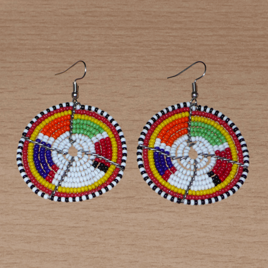 Boucles d'oreilles africaines de tradition tribale Massai composées de perles de rocaille blanches et multicolores montées en forme de disques. Elles mesurent 6.5 cm de long et 4.5 cm de large et se portent sur des oreilles percées.