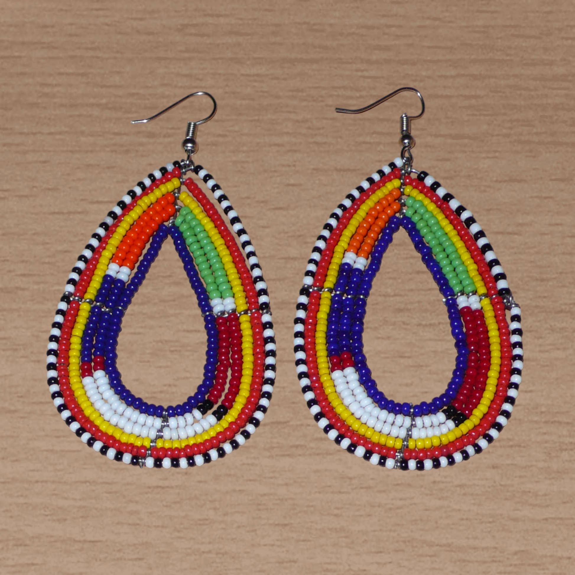 Apportez une touche ethnique à votre look avec ces longues boucles d'oreilles africaines traditionnelles aux couleurs et motifs tribaux Massai. Confectionnées selon la tradition artisanale kenyane, elles se composent de perles de rocaille bleu foncé et multicolores enfilées sur six rangées de fils de fer montés en forme de gouttes. Ces boucles d'oreilles mesurent 8.5 cm de long et 4 cm de large ; elles se portent avec des crochets en acier inoxydable sur des oreilles percées.
