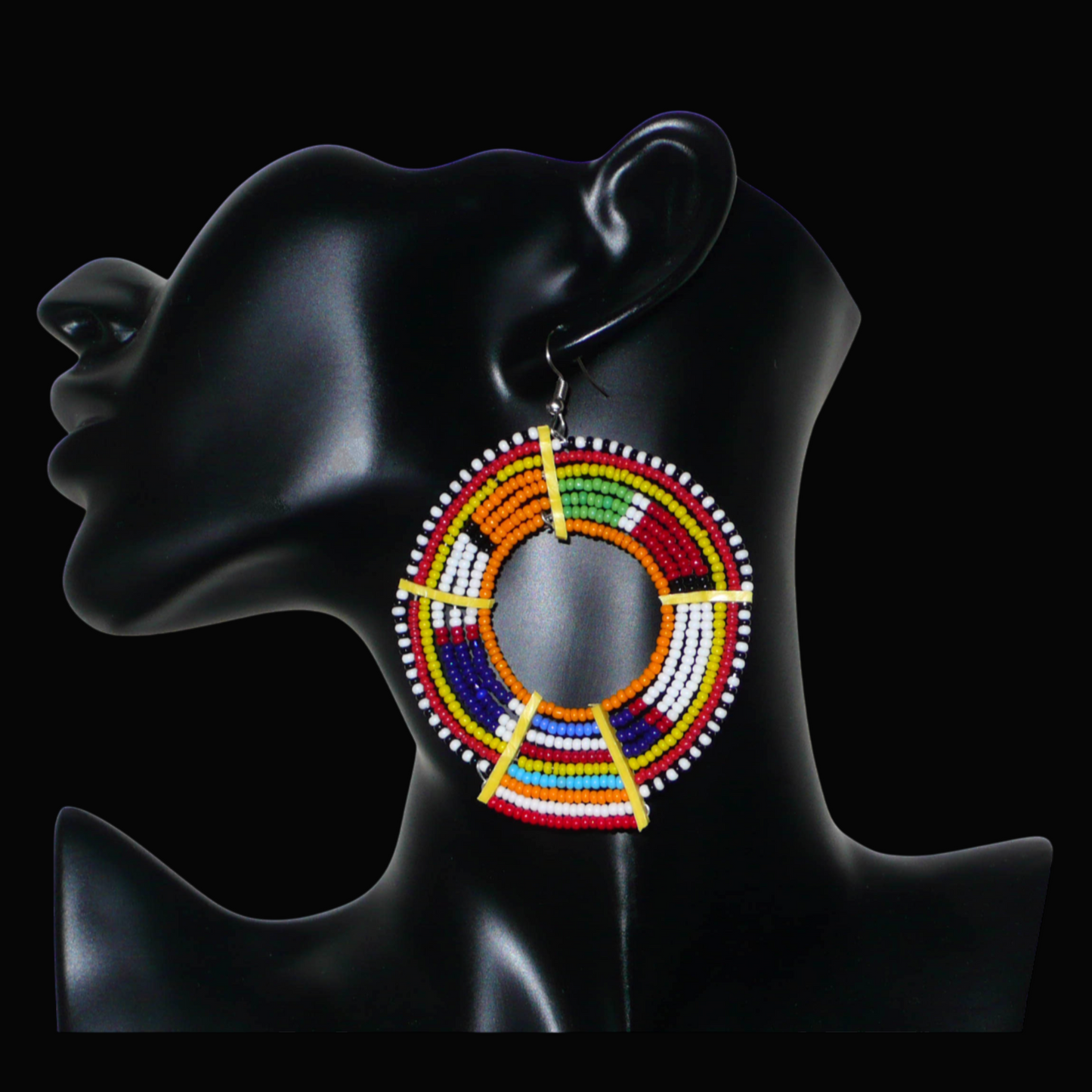 Boucles d'oreilles africaines tribales surdimensionnées, fabriquées au Kenya dans la plus pure tradition artisanale Massai. Elles se composent de perles de rocaille orange et multicolores tissées sur des structures circulaires en fils de fer fixés à des charnières en plastique jaune. Ces longues et larges boucles d'oreilles ethniques mesurent 8.5 cm de long et 6 cm de large ; elles se portent avec des crochets en acier inoxydable sur des oreilles percées.