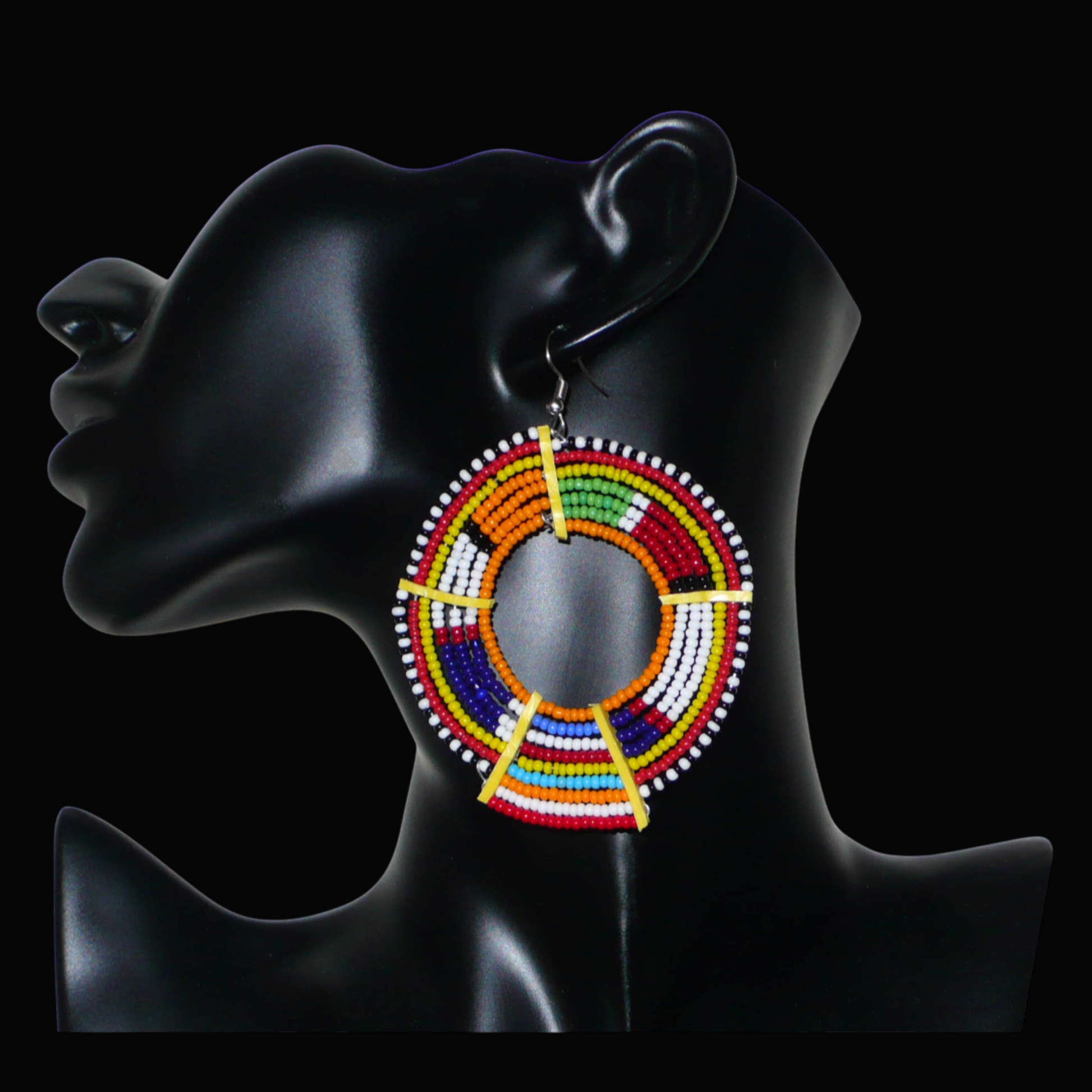 Boucles d'oreilles africaines tribales surdimensionnées, fabriquées au Kenya dans la plus pure tradition artisanale Massai. Elles se composent de perles de rocaille orange et multicolores tissées sur des structures circulaires en fils de fer fixés à des charnières en plastique jaune. Ces longues et larges boucles d'oreilles ethniques mesurent 8.5 cm de long et 6 cm de large ; elles se portent avec des crochets en acier inoxydable sur des oreilles percées.