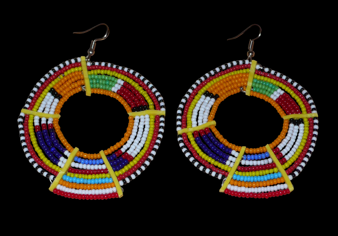 Boucles d'oreilles africaines tribales surdimensionnées, fabriquées au Kenya dans la plus pure tradition artisanale Massai. Elles se composent de perles de rocaille orange et multicolores tissées sur des structures circulaires en fils de fer fixés à des charnières en plastique jaune. Ces longues et larges boucles d'oreilles ethniques mesurent 8.5 cm de long et 6 cm de large ; elles se portent avec des crochets en acier inoxydable sur des oreilles percées.