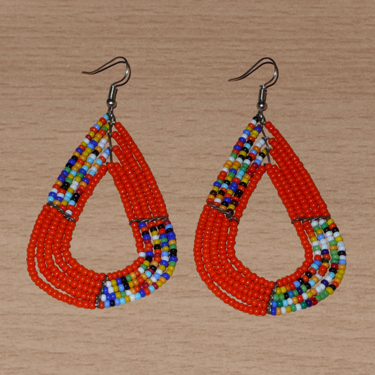 Boucles d'oreilles africaines multi-rangs aux couleurs évoquant le style afro des années 70 : elles se composent de perles de rocaille orange et d'un mélange de perles multicolores glissées sur cinq rangées de fils de fer en forme de gouttes légèrement triangulaires. Ces boucles d'oreilles kenyanes mesurent 8.5 cm de long et 4.5 cm de large ; elles se portent avec des crochets en acier inoxydable sur des oreilles percées.