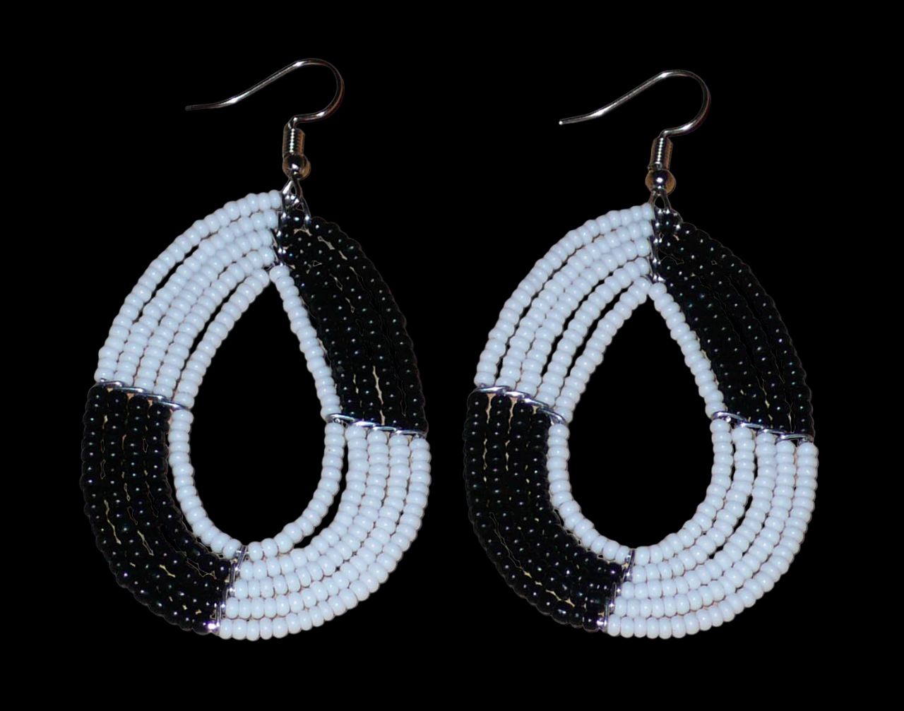 Boucles d'oreilles bicolores noires et blanches en forme de gouttes faites de perles de rocaille enfilées sur cinq rangées de fils. Elles mesurent 7,5 cm de long et 3 cm de large et se portent sur des oreilles percées.