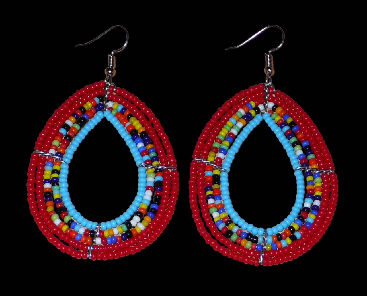 Boucles d'oreilles en forme de gouttes composées de perles de rocaille rouges, bleues et multicolores. Elles mesurent 7,5 cm de long et 4 cm de large et se portent sur des oreilles percées. Photographiées sur un fond noir.
