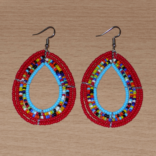 Boucles d'oreilles en forme de gouttes faites de perles de rocaille rouges, bleues et multicolores. Elles mesurent 7,5 cm de long et 4 cm de large et se portent sur des oreilles percées.