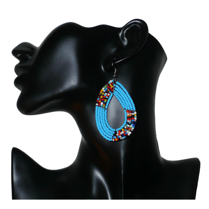 Boucles d'oreilles ethniques multi-rangs composées de perles bleu ciel et multicolores glissées sur cinq rangs de fils de fer montés en forme de gouttes. De taille moyenne, ces boucles d'oreilles kenyanes aux accents bohème mesurent 7,5 cm de long et 4 cm de large ; elles se portent avec des crochets en acier inoxydable.