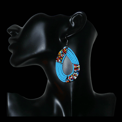 Boucles d'oreilles ethniques multi-rangs composées de perles bleu ciel et multicolores glissées sur cinq rangs de fils de fer montés en forme de gouttes. De taille moyenne, ces boucles d'oreilles kenyanes aux accents bohème mesurent 7,5 cm de long et 4 cm de large ; elles se portent avec des crochets en acier inoxydable.