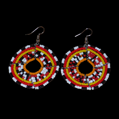 Boucles d'oreilles ethniques rondes composées d'un mélange de perles de rocaille rouges, jaunes, orange, blanches et noires. De taille moyenne, elles mesurent 6.5 cm de long et 4.5 cm de large et se portent sur des oreilles percées.