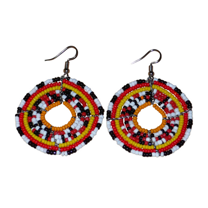 Boucles d'oreilles ethniques rondes composées d'un mélange de perles de rocaille rouges, jaunes, orange, blanches et noires. De taille moyenne, elles mesurent 6.5 cm de long et 4.5 cm de large et se portent sur des oreilles percées.