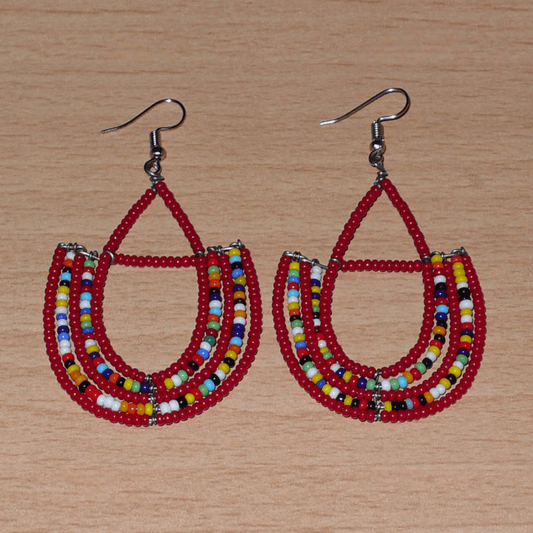 Boucles d'oreilles ethniques en forme d'ancres composées de perles de rocaille rouges et d'un mélange de perles multicolores ; elles mesurent 7,5 cm de long et 4 cm de large et se portent avec des crochets en acier inoxydable sur des oreilles percées.