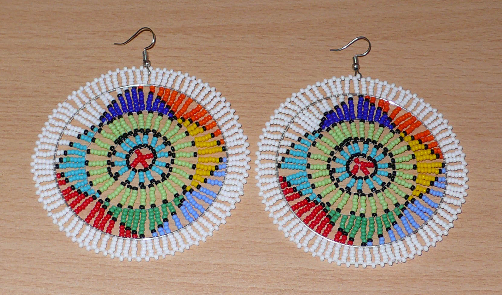 Boucles d'oreilles africaines à motifs ethniques sud-africains composées de perles de rocaille blanches et multicolores. Surdimensionnées, elles mesurent 10 cm de long et 8.5 cm de large.