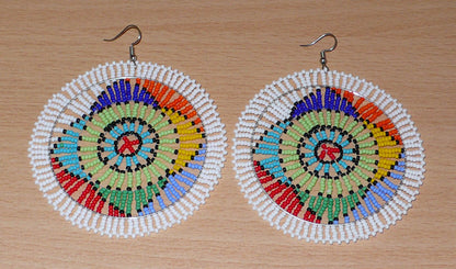 Boucles d'oreilles africaines à motifs ethniques sud-africains composées de perles de rocaille blanches et multicolores. Surdimensionnées, elles mesurent 10 cm de long et 8.5 cm de large.
