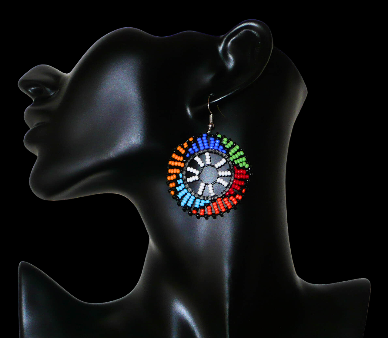 Boucles d'oreilles ethniques rondes à motifs sud-africains zoulous composées de perles de rocaille blanches et multicolores. De taille moyenne et légères à porter, elles mesurent 6 cm de long et 4 cm de large, et se portent sur des oreilles percées.
