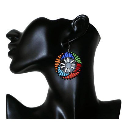 Boucles d'oreilles ethniques rondes à motifs sud-africains zoulous composées de perles de rocaille blanches et multicolores. De taille moyenne et légères à porter, elles mesurent 6 cm de long et 4 cm de large, et se portent sur des oreilles percées.