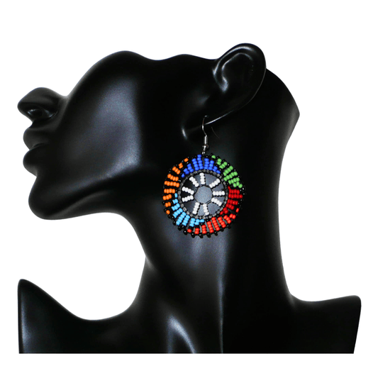 Boucles d'oreilles ethniques rondes à motifs sud-africains zoulous composées de perles de rocaille blanches et multicolores. De taille moyenne et légères à porter, elles mesurent 6 cm de long et 4 cm de large, et se portent sur des oreilles percées.