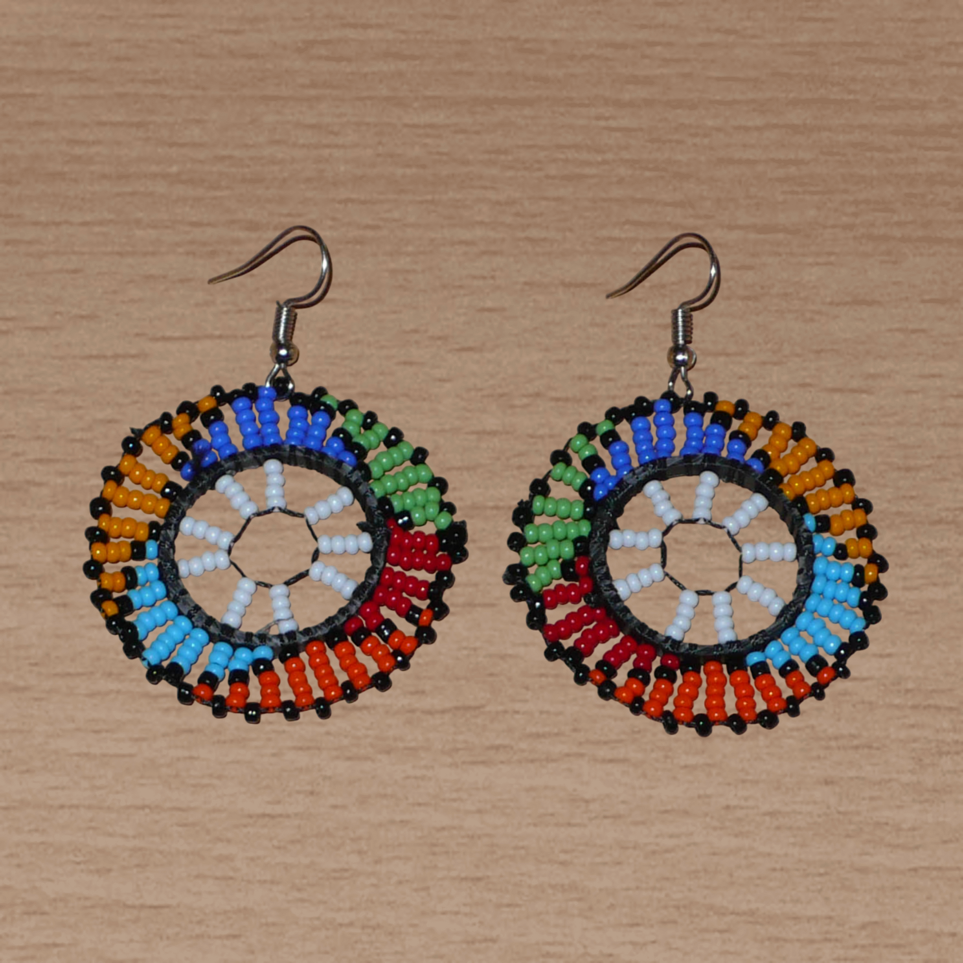 Boucles d'oreilles ethniques rondes à motifs sud-africains zoulous composées de perles de rocaille blanches et multicolores. De taille moyenne et légères à porter, elles mesurent 6 cm de long et 4 cm de large, et se portent sur des oreilles percées.