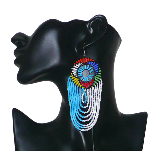 Longues boucles d'oreilles sud-africaines zouloues, rondes à franges perlées, composées de perles de rocaille bleu ciel, blanches et multicolores. Elles mesurent 12 cm de long et 4.5 cm de large, et se potent sur des oreilles percées.