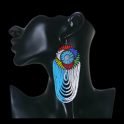 Longues boucles d'oreilles sud-africaines zouloues, rondes à franges perlées, composées de perles de rocaille bleu ciel, blanches et multicolores. Elles mesurent 12 cm de long et 4.5 cm de large, et se potent sur des oreilles percées.