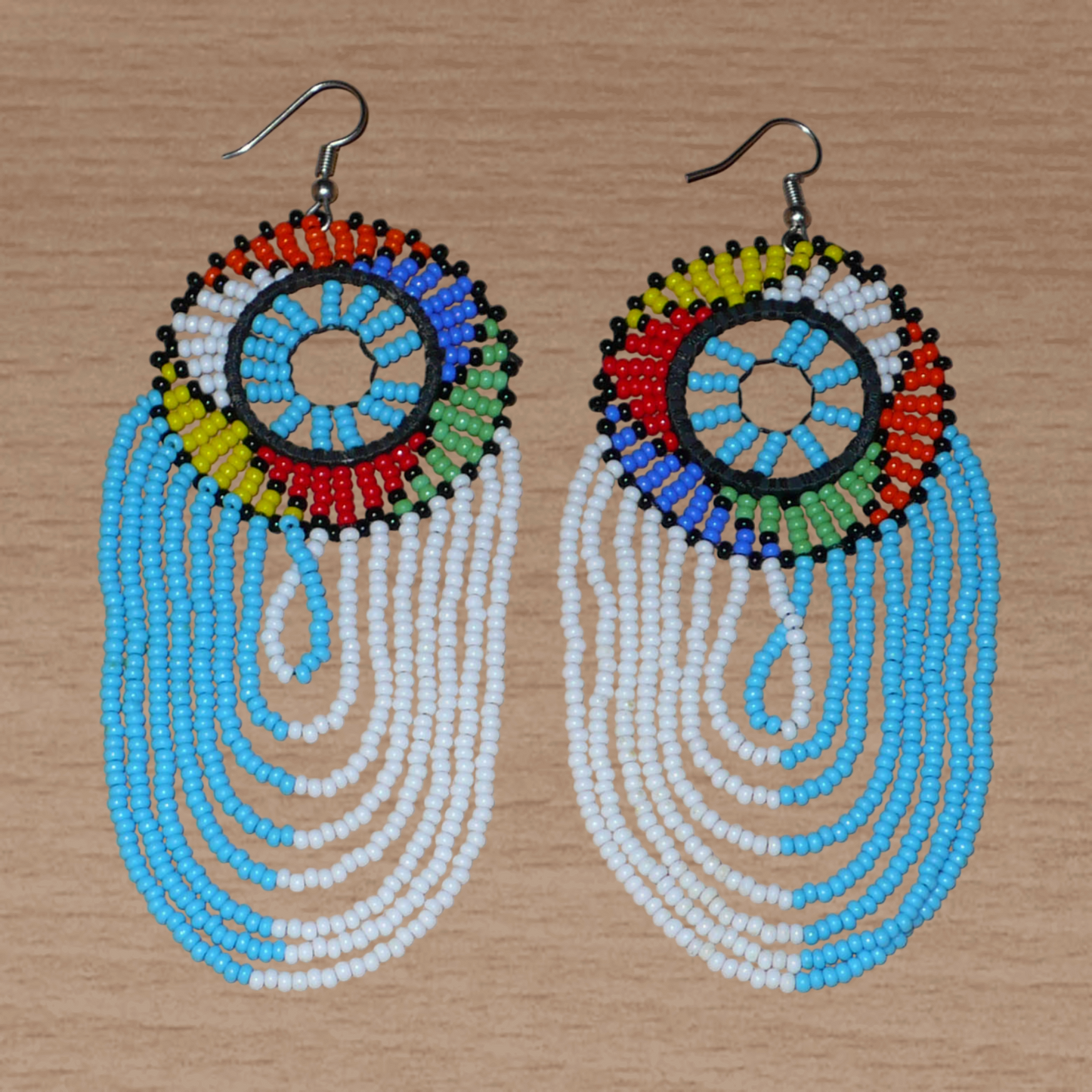 Longues boucles d'oreilles sud-africaines zouloues, rondes à franges perlées, composées de perles de rocaille bleu ciel, blanches et multicolores. Elles mesurent 12 cm de long et 4.5 cm de large, et se potent sur des oreilles percées.