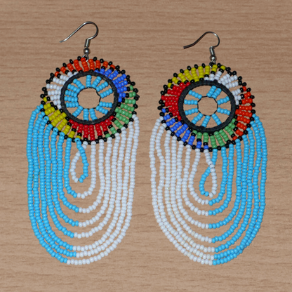 Longues boucles d'oreilles sud-africaines zouloues, rondes à franges perlées, composées de perles de rocaille bleu ciel, blanches et multicolores. Elles mesurent 12 cm de long et 4.5 cm de large, et se potent sur des oreilles percées.