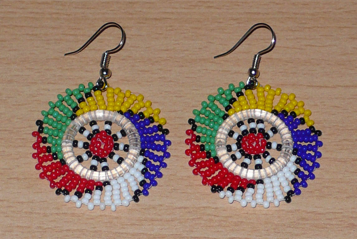 Boucles d'oreilles sud-africaines rondes à motifs traditionnels zoulous faites de perles de rocaille multicolores. Elles mesurent 6 cm de long et 4 cm de large et se portent sur des oreilles percées.