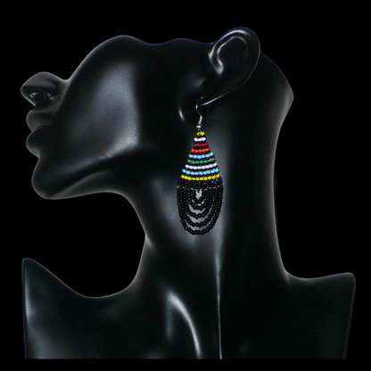 Boucles d'oreilles ethniques de tradition sud-africaine en forme de gouttes composées d'un tissage de perles de rocaille noires et multicolores. Elles mesurent 7 cm de long et 2,5 cm de large et se portent sur des oreilles percées.