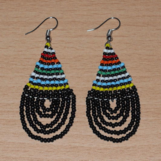 Boucles d'oreilles ethniques de tradition sud-africaine en forme de gouttes composées d'un tissage de perles de rocaille noires et multicolores. Elles mesurent 7 cm de long et 2,5 cm de large et se portent sur des oreilles percées.