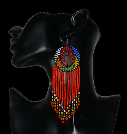 Longues boucles d'oreilles sud-africaines à franges et motifs traditionnels zoulous composées de perles de rocaille orange et multicolores. Elles mesurent 14,5 cm de long et 4,5 cm de large.