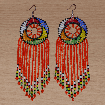 Longues boucles d'oreilles sud-africaines à franges et motifs traditionnels zoulous composées de perles de rocaille orange et multicolores. Elles mesurent 14,5 cm de long et 4,5 cm de large.