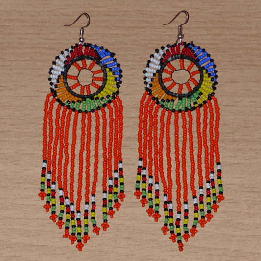 Longues boucles d'oreilles sud-africaines à franges et motifs traditionnels zoulous composées de perles de rocaille orange et multicolores. Elles mesurent 14,5 cm de long et 4,5 cm de large.