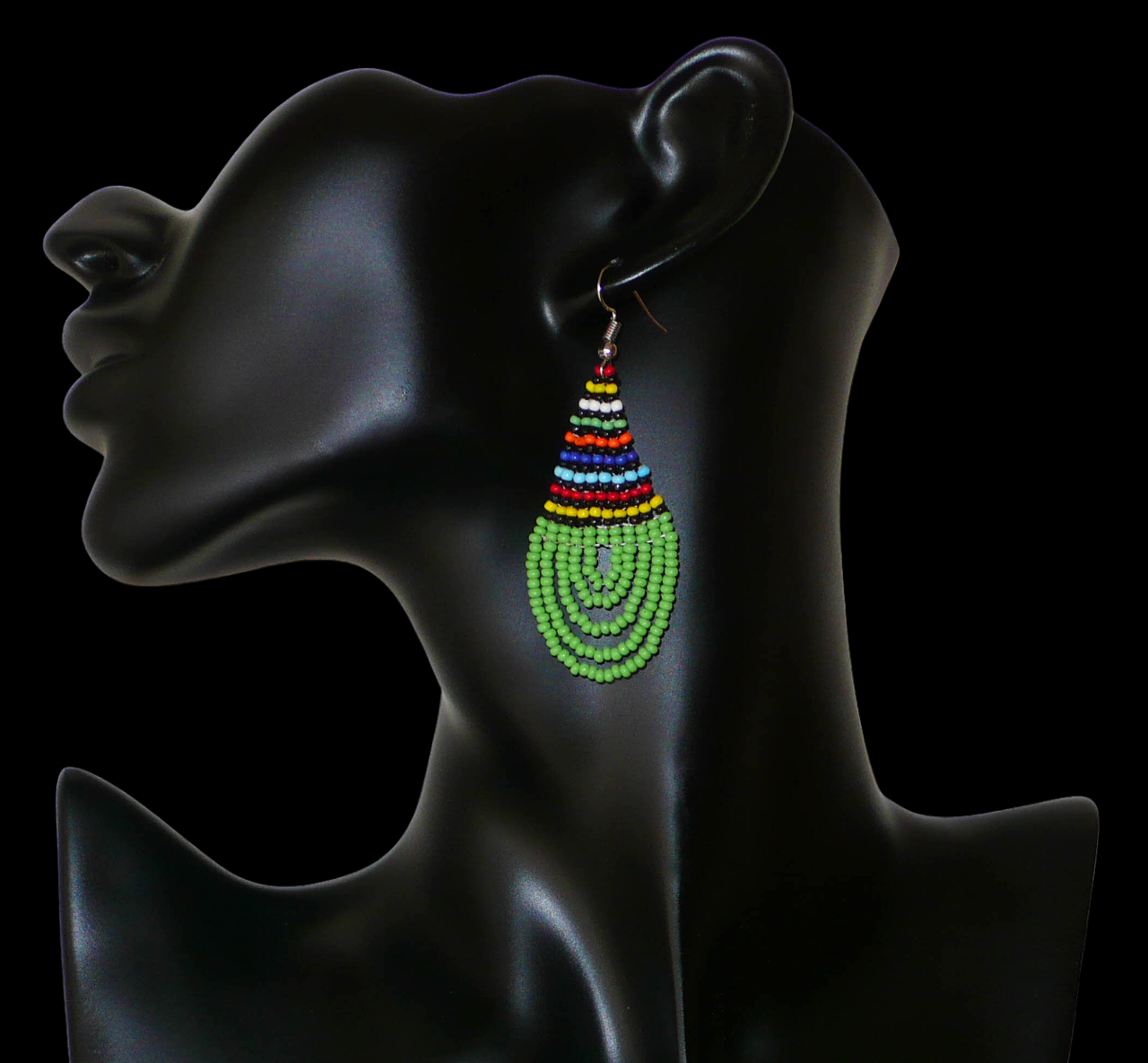 Boucles d'oreilles africaines traditionnelles zouloues en forme de gouttes faites d'un tissage de perles de rocaille vertes et multicolores. Elles mesurent 7 cm de long et 2,5 cm de large et se portent sur des oreilles percées.