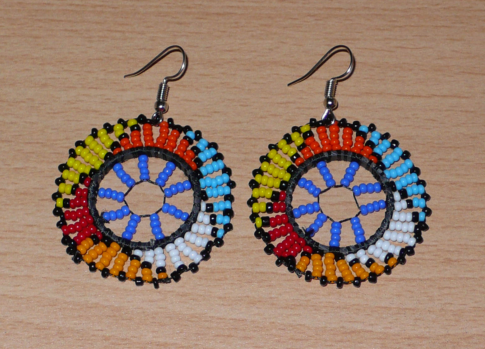 Boucles d'oreilles africaines rondes à motifs ethniques zoulous composées de perles de rocaille bleues et multicolores. De taille moyenne et légères à porter, elles mesurent 6 cm de long et 4 cm de large. Elles se portent avec des crochets en acier inoxydable sur des oreilles percées.