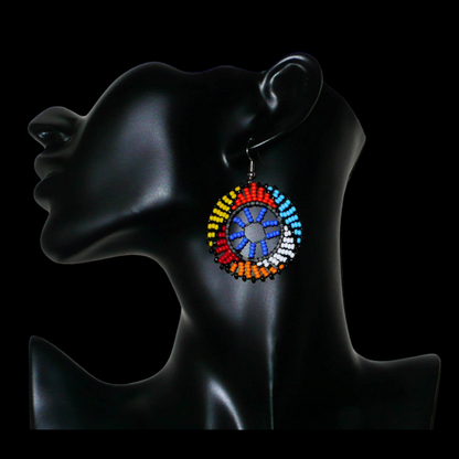 Boucles d'oreilles africaines rondes à motifs ethniques zoulous composées de perles de rocaille bleues et multicolores. De taille moyenne et légères à porter, elles mesurent 6 cm de long et 4 cm de large. Elles se portent avec des crochets en acier inoxydable sur des oreilles percées.