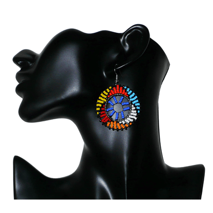 Boucles d'oreilles africaines rondes à motifs ethniques zoulous composées de perles de rocaille bleues et multicolores. De taille moyenne et légères à porter, elles mesurent 6 cm de long et 4 cm de large. Elles se portent avec des crochets en acier inoxydable sur des oreilles percées.
