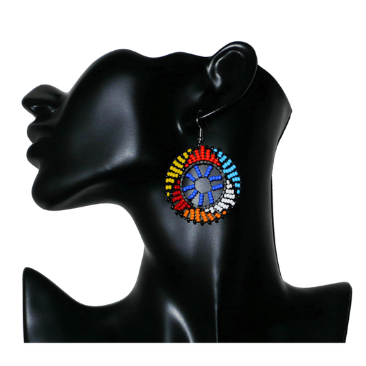 Boucles d'oreilles africaines rondes à motifs ethniques zoulous composées de perles de rocaille bleues et multicolores. De taille moyenne et légères à porter, elles mesurent 6 cm de long et 4 cm de large. Elles se portent avec des crochets en acier inoxydable sur des oreilles percées.