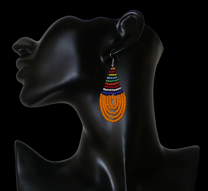 Boucles d'oreilles africaines traditionnelles en forme de gouttes composées d'un tissage de perles de rocaille orange et multicolores. Elles mesurent 7 cm de long et 2,5 cm de large. 