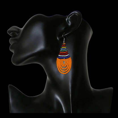 Boucles d'oreilles africaines traditionnelles en forme de gouttes composées d'un tissage de perles de rocaille orange et multicolores. Elles mesurent 7 cm de long et 2,5 cm de large. 