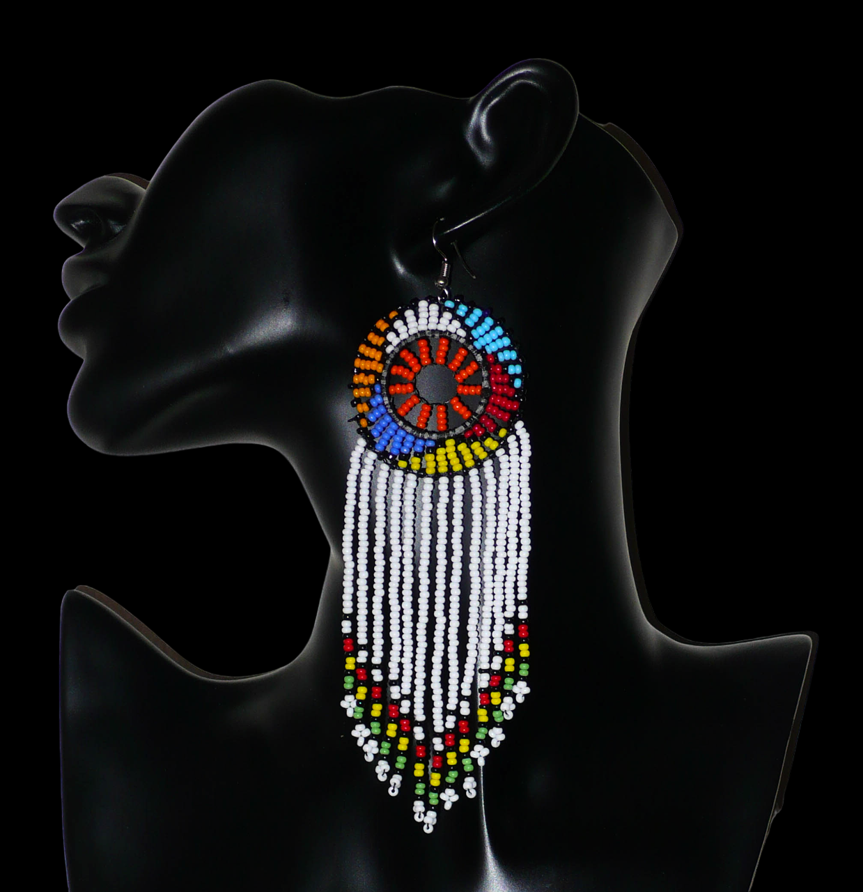 Longues boucles d'oreilles sud-africaines à franges et motifs traditionnels zoulous composées de perles de rocaille blanches, orange et multicolores. Elles mesurent 14,5 cm de long et 4,5 cm de large, et se portent avec des crochets en acier inoxydable sur des oreilles percées.