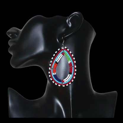 Boucles d'oreilles africaines à motifs ethniques Massai faites de perles de rocaille multicolores montées en forme de gouttes. Elles mesurent 8,5 cm de long et 4,5 cm de large et se portent sur des oreilles percées.