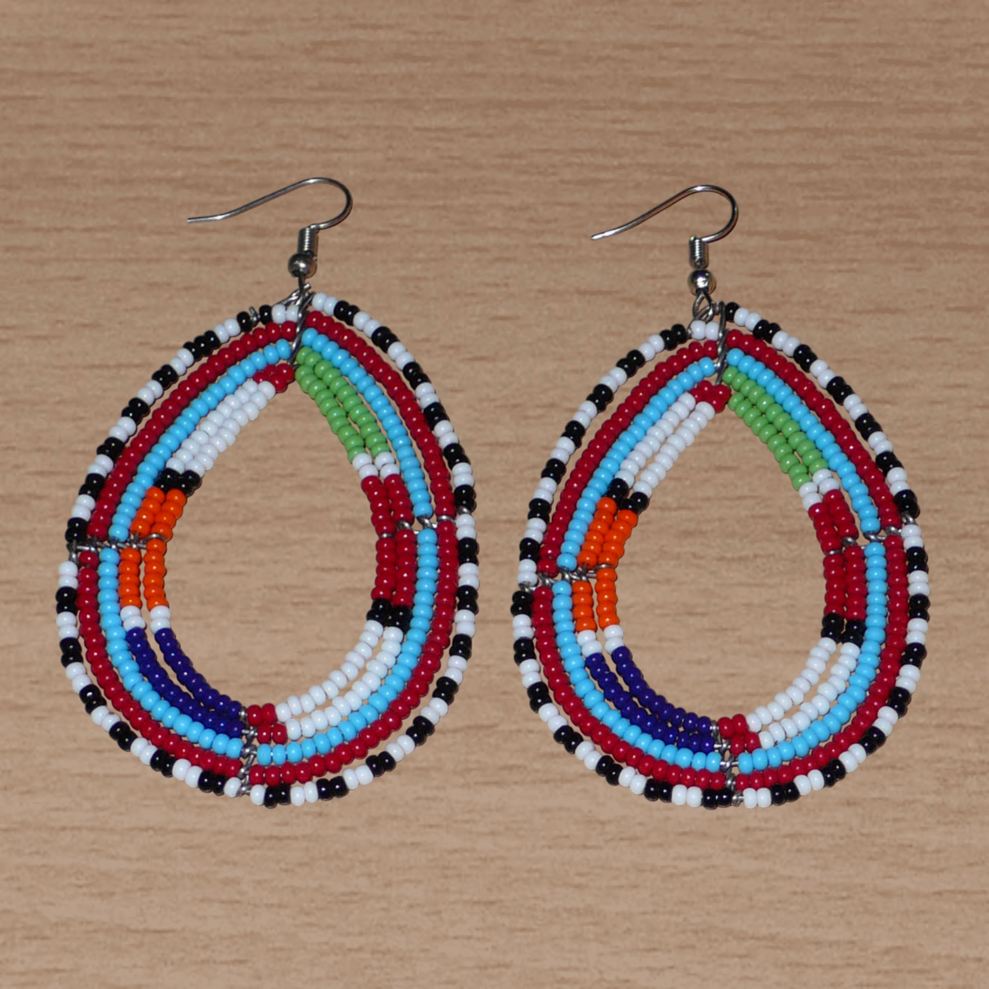 Boucles d'oreilles africaines à motifs ethniques Massai faites de perles de rocaille multicolores montées en forme de gouttes. Elles mesurent 8,5 cm de long et 4,5 cm de large et se portent sur des oreilles percées.