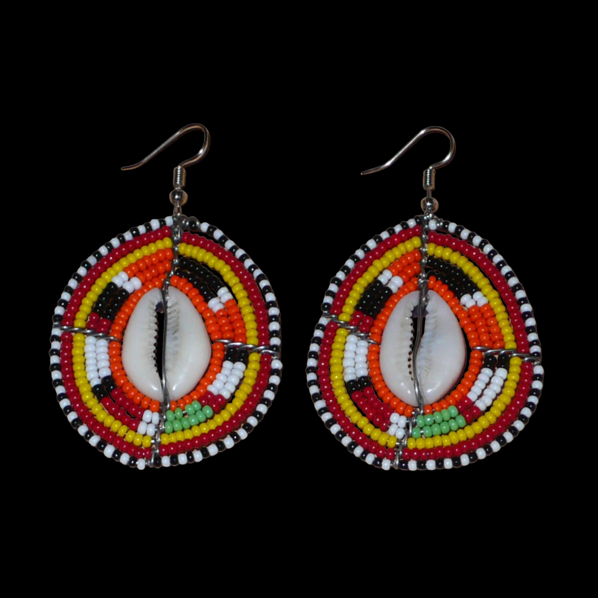 Boucles d'oreilles africaines en forme de boucliers Massai composées de perles et de coquillages. Elles mesurent 7 cm de long et 4 cm de large et se portent sur des oreilles percées.