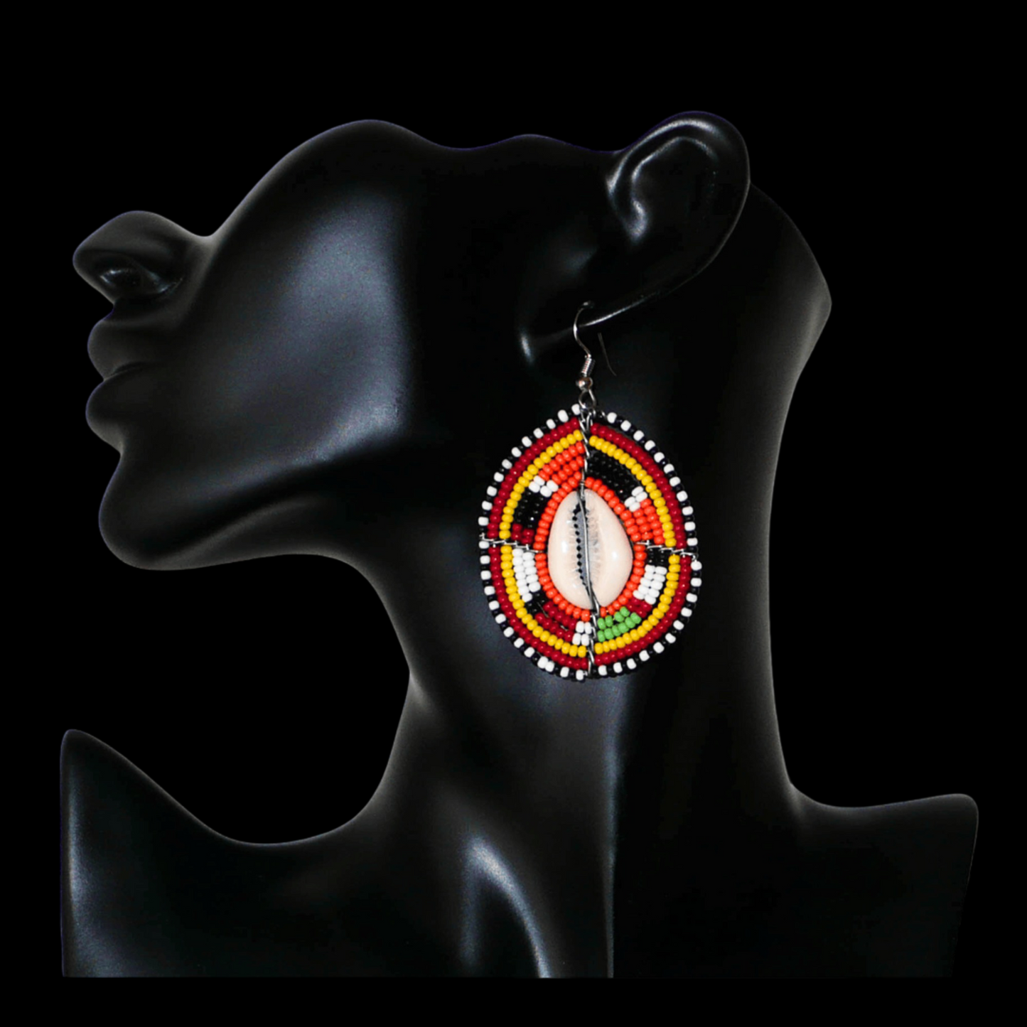 Boucles d'oreilles africaines en forme de boucliers Massai composées de perles et de coquillages. Elles mesurent 7 cm de long et 4 cm de large et se portent sur des oreilles percées.