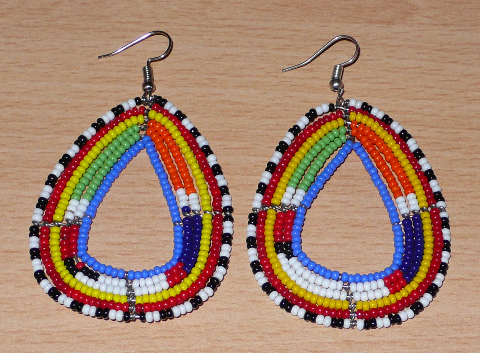 Boucles d'oreilles tribales Massai bleues et multicolores faites de perles de rocaille montées en forme de gouttes légèrement triangulaires. Elles mesurent 8 cm de long et 4.5 cm de large et se portent sur des oreilles percées.