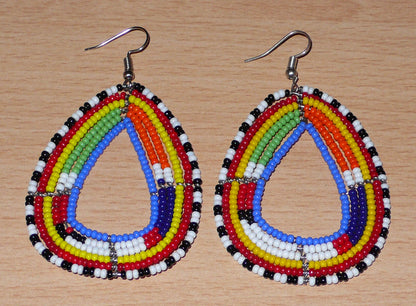 Boucles d'oreilles tribales Massai bleues et multicolores faites de perles de rocaille montées en forme de gouttes légèrement triangulaires. Elles mesurent 8 cm de long et 4.5 cm de large et se portent sur des oreilles percées.