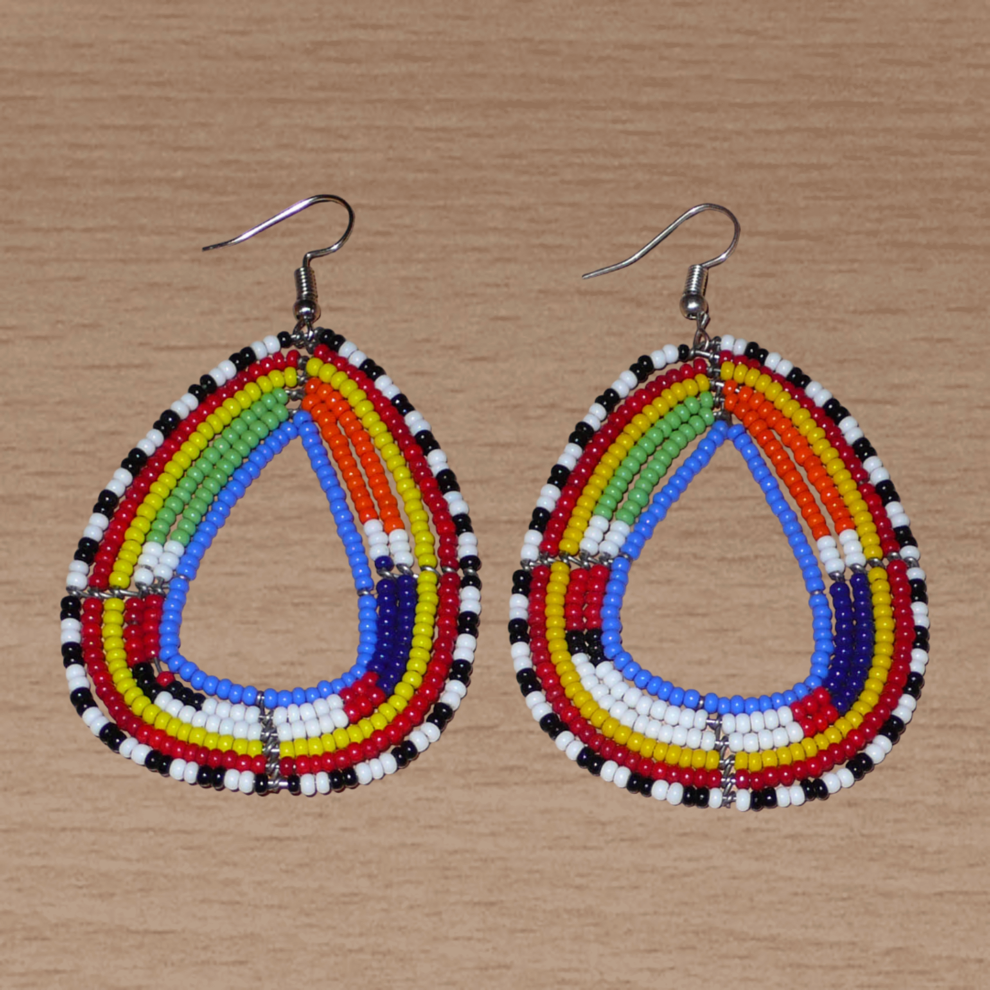 Boucles d'oreilles tribales Massai bleues et multicolores faites de perles de rocaille montées en forme de gouttes légèrement triangulaires. Elles mesurent 8 cm de long et 4.5 cm de large et se portent sur des oreilles percées.