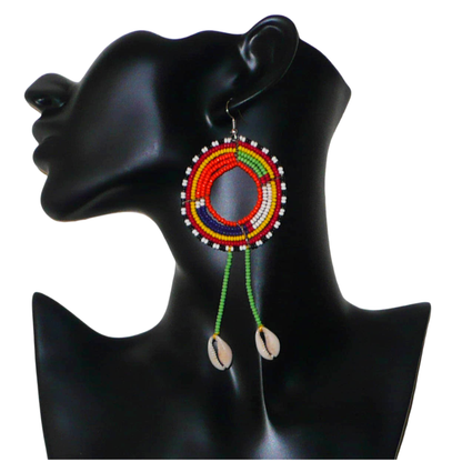 Longues boucles d'oreilles africaines tribales Massai composées de perles de rocaille vertes et multicolores glissées sur une structure ronde en fils de fer et prolongées de franges perlées ornées de coquillages. Elles mesurent 12.5 cm de long et 5 cm de large et se portent sur des oreilles percées.
