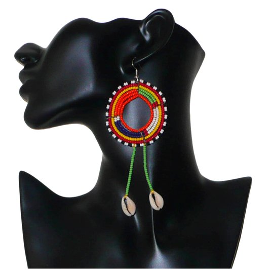 Longues boucles d'oreilles africaines tribales Massai composées de perles de rocaille vertes et multicolores glissées sur une structure ronde en fils de fer et prolongées de franges perlées ornées de coquillages. Elles mesurent 12.5 cm de long et 5 cm de large et se portent sur des oreilles percées.