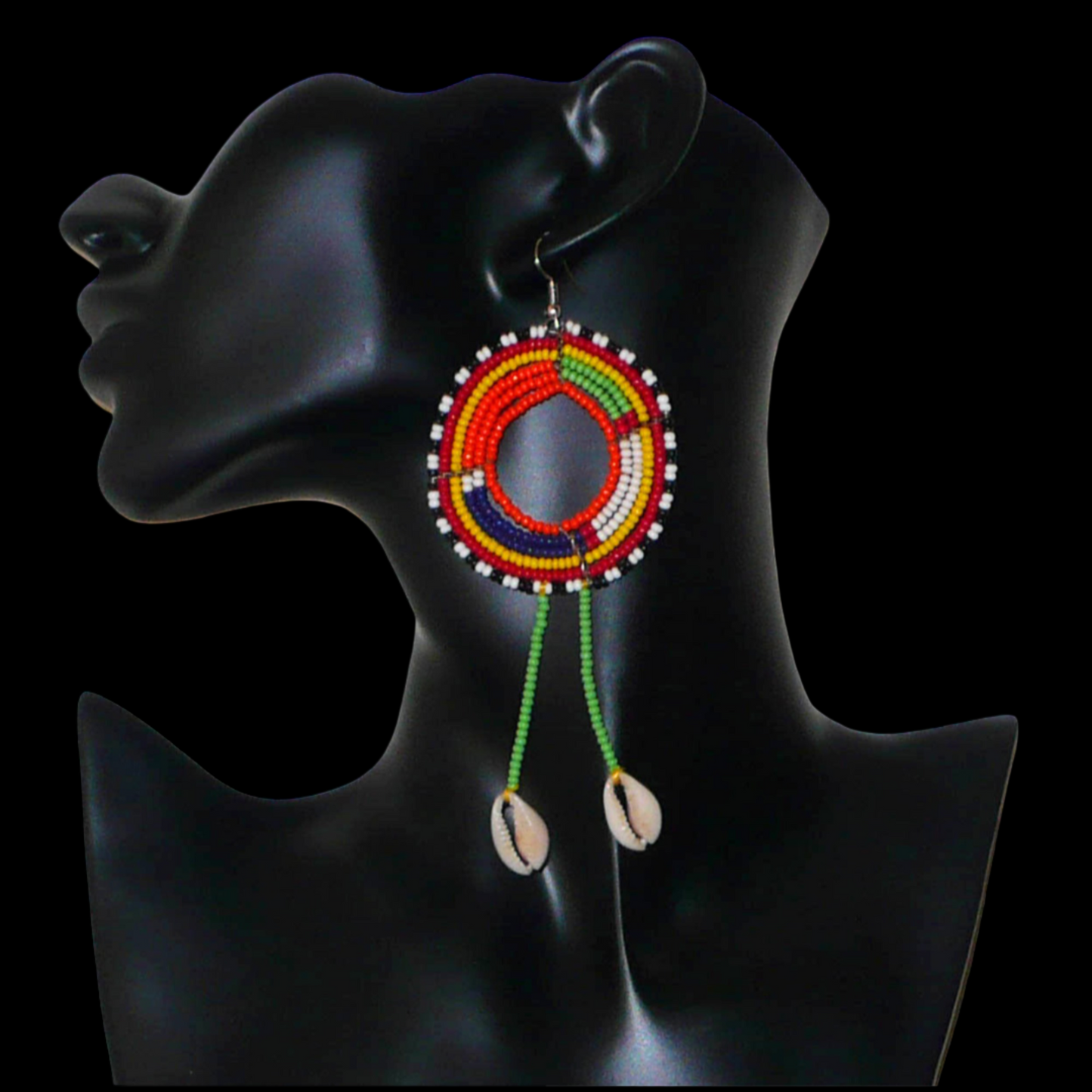 Longues boucles d'oreilles africaines tribales Massai composées de perles de rocaille vertes et multicolores glissées sur une structure ronde en fils de fer et prolongées de franges perlées ornées de coquillages. Elles mesurent 12.5 cm de long et 5 cm de large et se portent sur des oreilles percées.