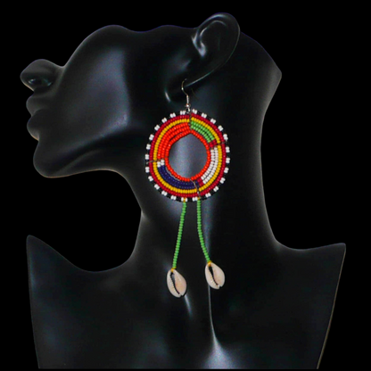 Longues boucles d'oreilles africaines tribales Massai composées de perles de rocaille vertes et multicolores glissées sur une structure ronde en fils de fer et prolongées de franges perlées ornées de coquillages. Elles mesurent 12.5 cm de long et 5 cm de large et se portent sur des oreilles percées.